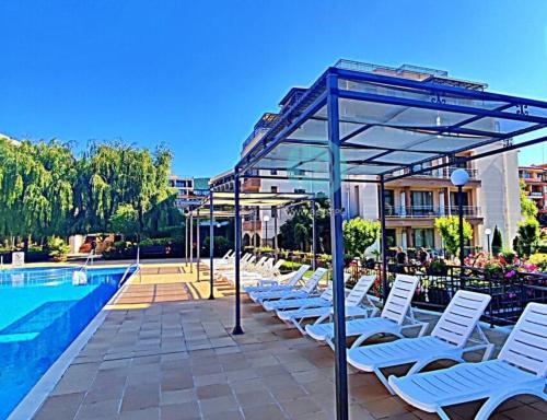 een rij witte ligstoelen naast een zwembad bij Sorrento Sole Mare - Apartments by the beach in Sveti Vlas