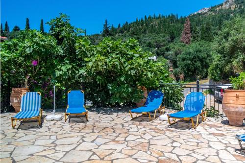 three blue chairs sitting on a stone patio at Arianna Studio 9b in Paleokastritsa