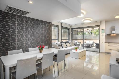 eine Küche und ein Wohnzimmer mit einem weißen Tisch und Stühlen in der Unterkunft Trust Inn garden in the city in Tel Aviv