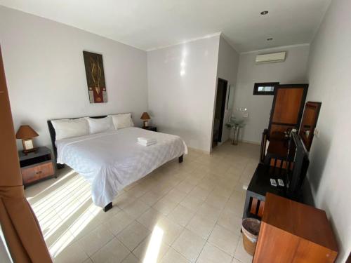 a bedroom with a white bed and a dresser in it at Puri Hasu Bali in Jimbaran