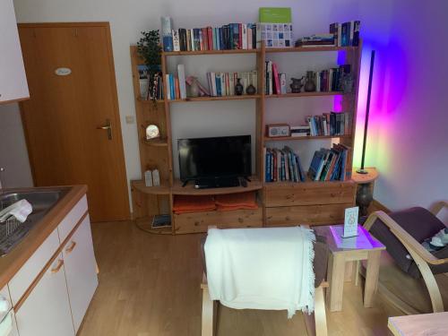 a living room with a tv and a table with a chair at Einladendes Appartement im Grünen für 2 Personen in Ostrach
