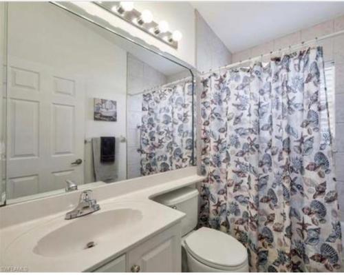 a bathroom with a sink and a toilet and a shower curtain at Marco Island Retreat- close to beach ! in Marco Island
