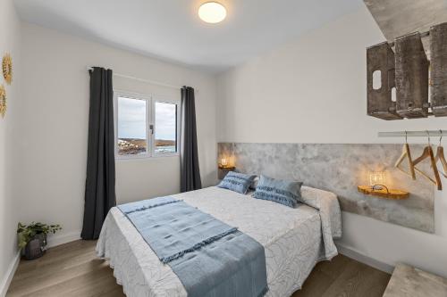 a white bedroom with a large bed with blue pillows at Casa Azul by Escape Home in Punta de Mujeres