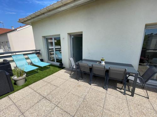 un patio avec une table et des chaises dans une cour dans l'établissement BnGo I Immense RoofTop Lyon I 2 chambres, 4 places parkings, 2 immenses terrasses, 8 personnes, à Lyon