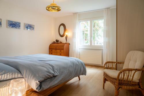 ein Schlafzimmer mit einem Bett, einem Stuhl und einem Fenster in der Unterkunft Chez Domi et Michou in Zermatt