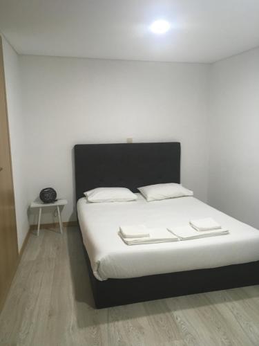 uma cama com lençóis brancos e almofadas num quarto em Casa do Castelo I em Brangança