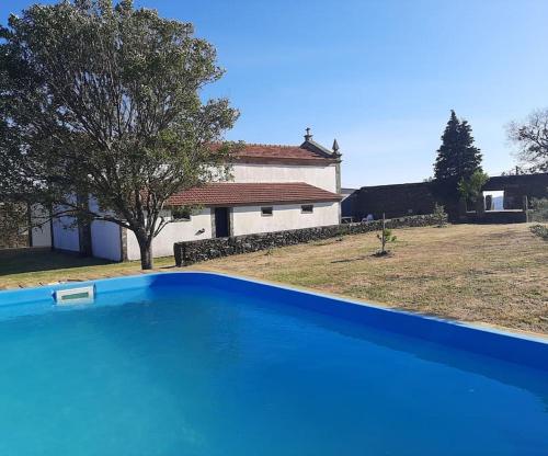 a blue swimming pool in front of a house at Quartéis de Santa Justa in Cerquido