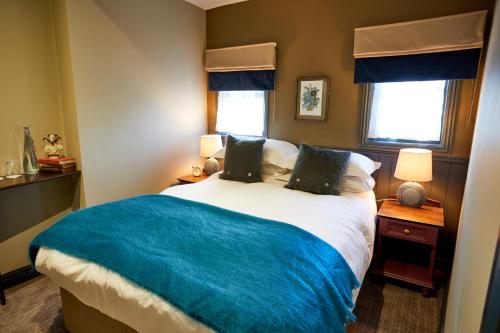 a bedroom with a large bed with a blue blanket at The Fleece at Cirencester in Cirencester