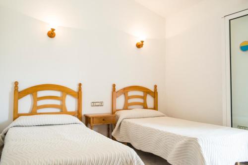 Habitación con 2 camas individuales y paredes blancas. en Apartchalet villas Elvira. Villa F, en Son Carrio