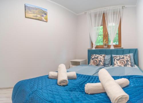 a bedroom with a blue bed with towels on it at Ostoja Leśna in Karpacz