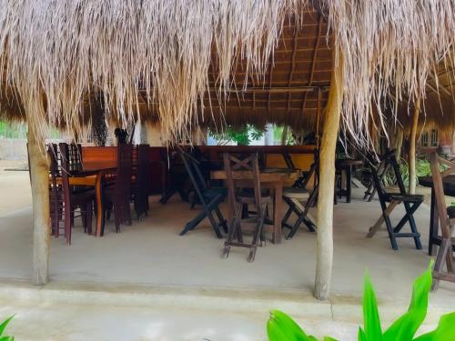 un restaurant avec une table et des chaises sous un toit de paille dans l'établissement The Crab Beach Resort, à Kandakuli