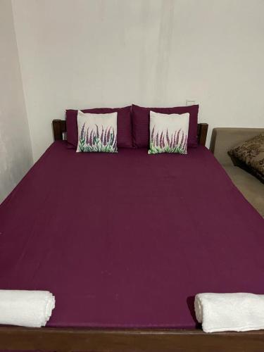 Cama púrpura con sábanas y almohadas púrpuras en The Crab Beach Resort en Kandakuli