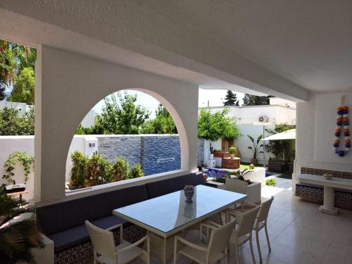 un patio con tavolo, sedie e piscina di Villa de Charme Adultes Only a Nabeul