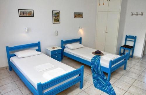 Dos camas azules en una habitación con sombrero en Pano sto Kyma Studios, en Plomari