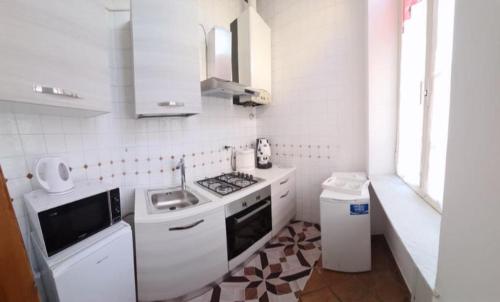 a white kitchen with a stove and a sink at La casa del Professore in Naples