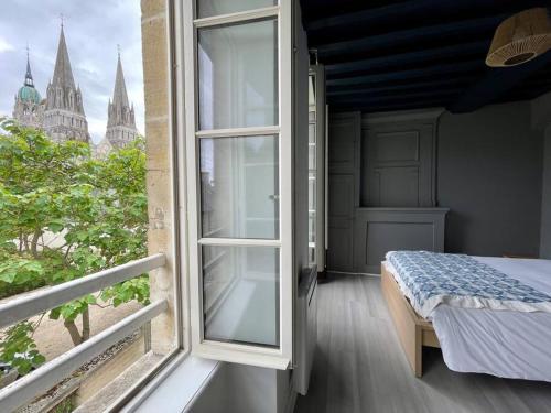 Schlafzimmer mit einem Bett und einem Fenster mit Aussicht in der Unterkunft Le Liberty by Melrose in Bayeux