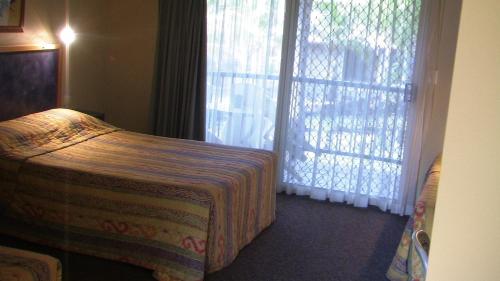 um quarto de hotel com uma cama e uma janela em Bushland Beach Tavern em Townsville