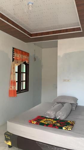 Bett in einem weißen Zimmer mit Fenster in der Unterkunft Gabe Homestay in Halangan