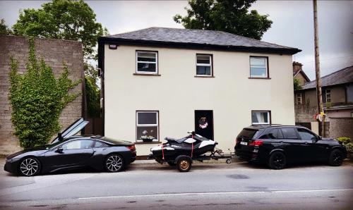 two cars parked in front of a house at Detached Town centre Villa in Cashel Sleeps 6 Private BBQ Area & Jacuzzi Bath in Cashel