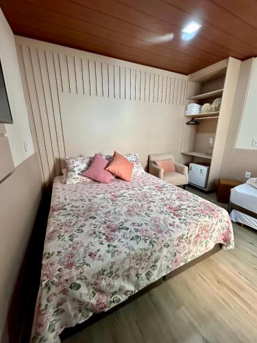 a bedroom with a bed with a floral comforter and a chair at Pousada Rota do Sol Quarto Filial Rose 11 in Penha