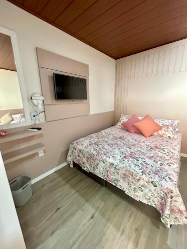 a bedroom with a bed with a tv on the wall at Pousada Rota do Sol Quarto Filial Rose 11 in Penha