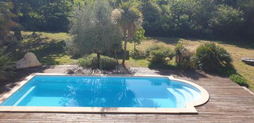 une piscine bleue dans une cour arborée dans l'établissement maison au calme avec piscine, à Vertheuil-en-Médoc