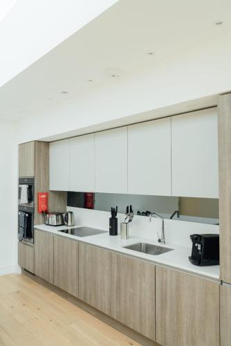 a kitchen with white cabinets and a sink at Access Brick Lane in London