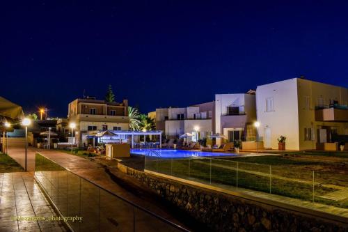 a group of buildings with a pool at night at Nautica Hotel Apartments in Stavromenos