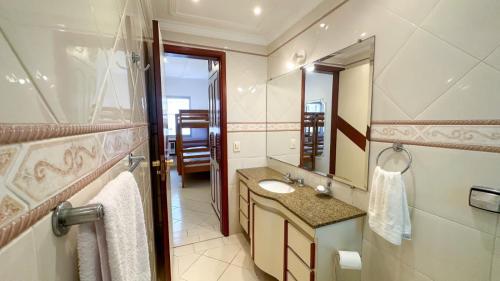 a bathroom with a sink and a mirror at Cobertura Guarujá in Guarujá