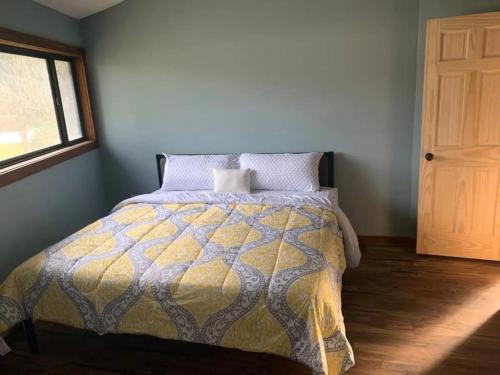 1 dormitorio con 1 cama con edredón amarillo y gris en Unique Octagon House near Cedar Point, en Huron
