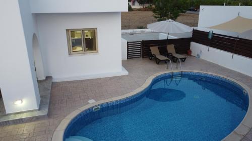una piscina junto a un edificio con sombrilla en Nireas Villa, en Pafos