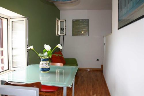 una sala de estar con una mesa de cristal con un jarrón de flores en B&B Trieste&Trento, en Nápoles