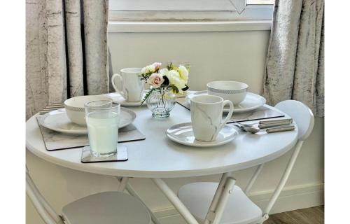 a white table with plates and glasses of milk at Cardiff City Centre Apartment- Penarth Road in Cardiff