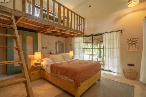 Un dormitorio con una cama elevada y una escalera en La Colmena RD, en Santa Bárbara de Samaná