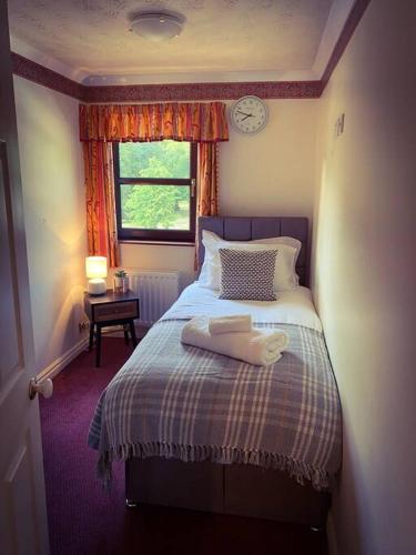 1 dormitorio con 1 cama con reloj en la pared en Home away from home, en Workington