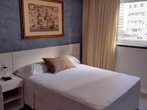 a bedroom with a large white bed and a window at Hotel Três Caravelas in Fortaleza