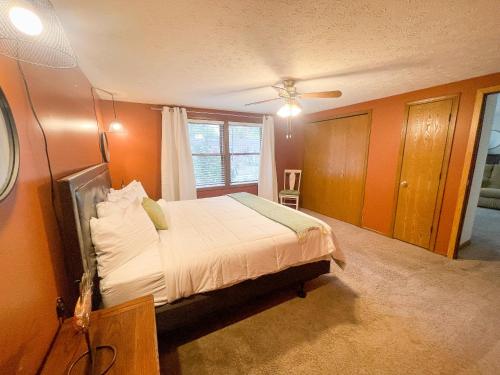 a bedroom with a bed with orange walls and a window at Rye Beach Family Cottage in Huron