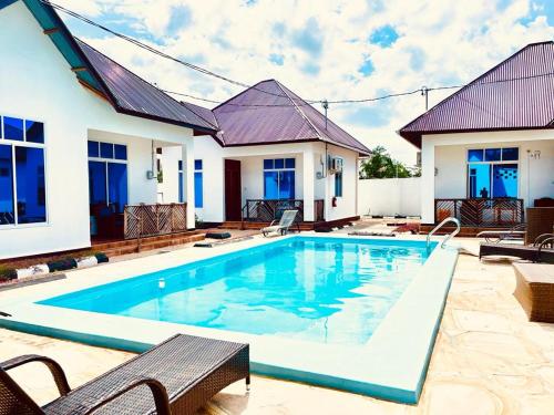 a swimming pool in front of a house at Mbuyu Uvi Apartment in Paje