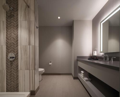 a bathroom with a sink and a toilet and a mirror at Great Canadian Casino Resort Toronto in Toronto