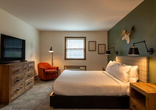 a bedroom with a bed and a television and a chair at Lodge at Schroon Lake in Schroon Lake