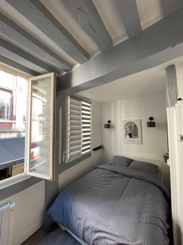 a small bedroom with a bed and two windows at Studio au cœur de Rouen in Rouen