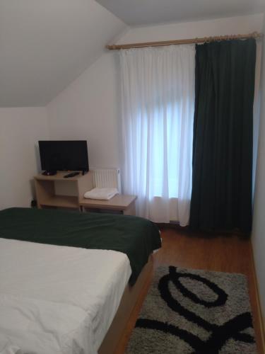 Schlafzimmer mit einem Bett und einem Schreibtisch mit einem Computer in der Unterkunft Casa Noastra in Orşova