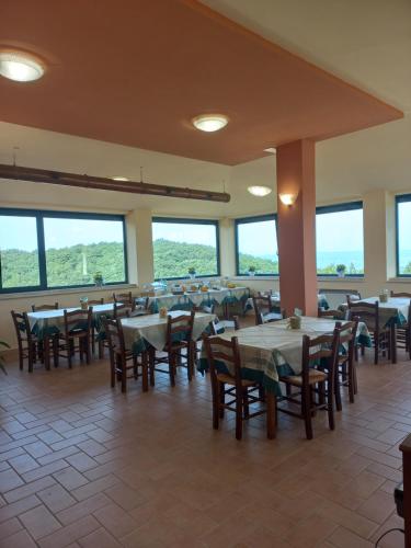 ein Esszimmer mit Tischen, Stühlen und Fenstern in der Unterkunft Agriturismo Trosciole in Massa Martana