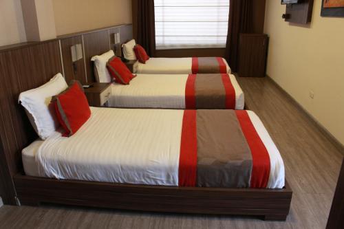 a hotel room with two beds with red pillows at Hotel Santiago de Compostella Suites in Cuenca