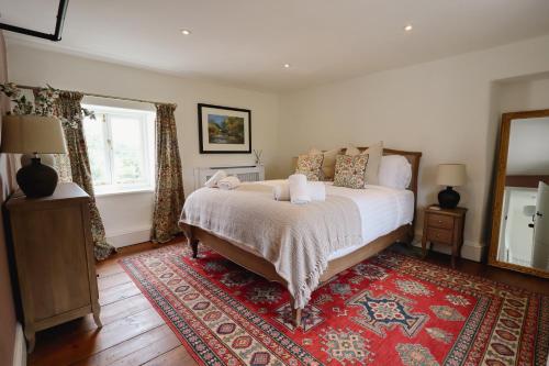 a bedroom with a large bed and a red rug at The Little Chantry - Hot Tub, Riverside, Pet Friendly in West Tanfield