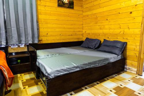 uma pequena cama num quarto com paredes de madeira em The Door to Nirvana Cottages em Coonoor