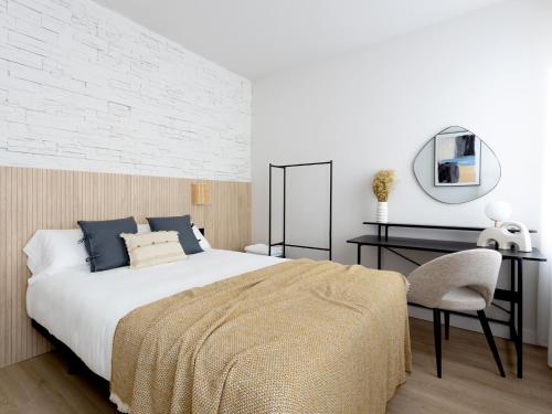 1 dormitorio con cama, escritorio y espejo en Meraki Suites, en Astorga