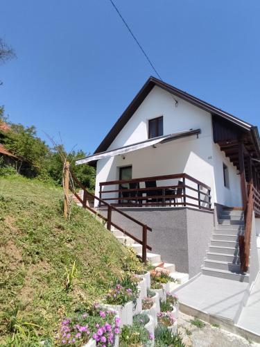 a white house with stairs and flowers on a hill at Kuća za odmor Obitelj Kušan in Veliki Erjavec