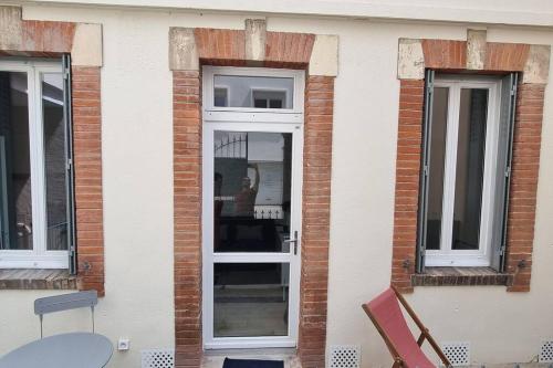 um edifício com duas janelas e uma porta com uma mesa em Grand studio avec terrasse - Gare - Metro - Wifi em Toulouse
