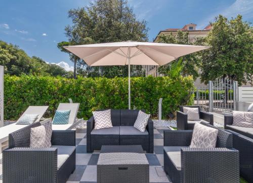 a patio with chairs and an umbrella at Hotel Tirreno in Marina di Massa